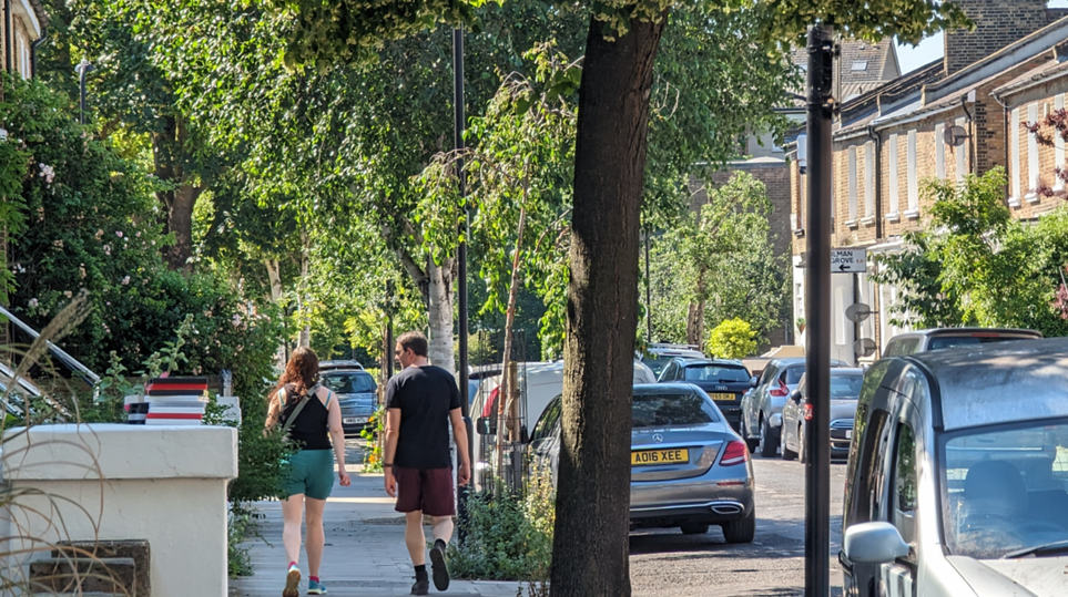 Man and woman walking past a tree