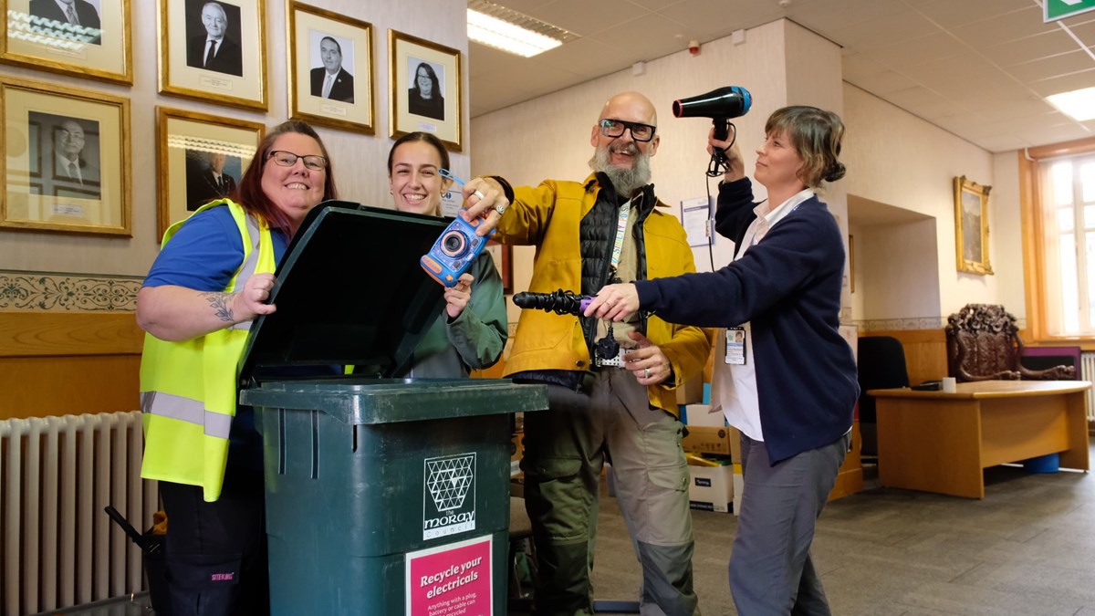Council officers clown around with Moray's Climate Change Champion, Cllr Draeyk Van Der Horn, as they put their broken and old electricals into one of the new staff e-waste recycling bins.
