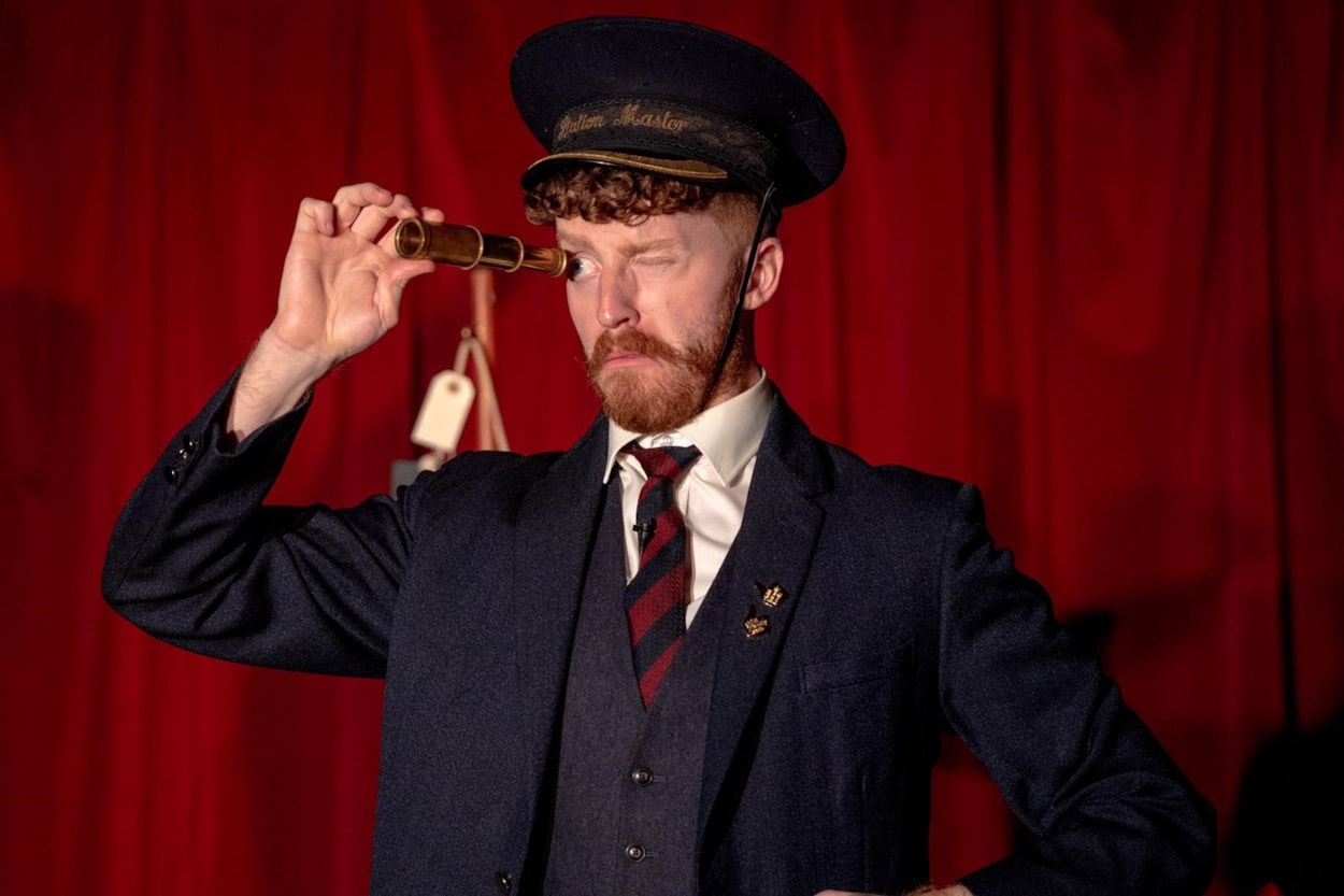 The Lost Property Library (Photo by Lian Furness): A man in a station master costume is looking through a small telescope.