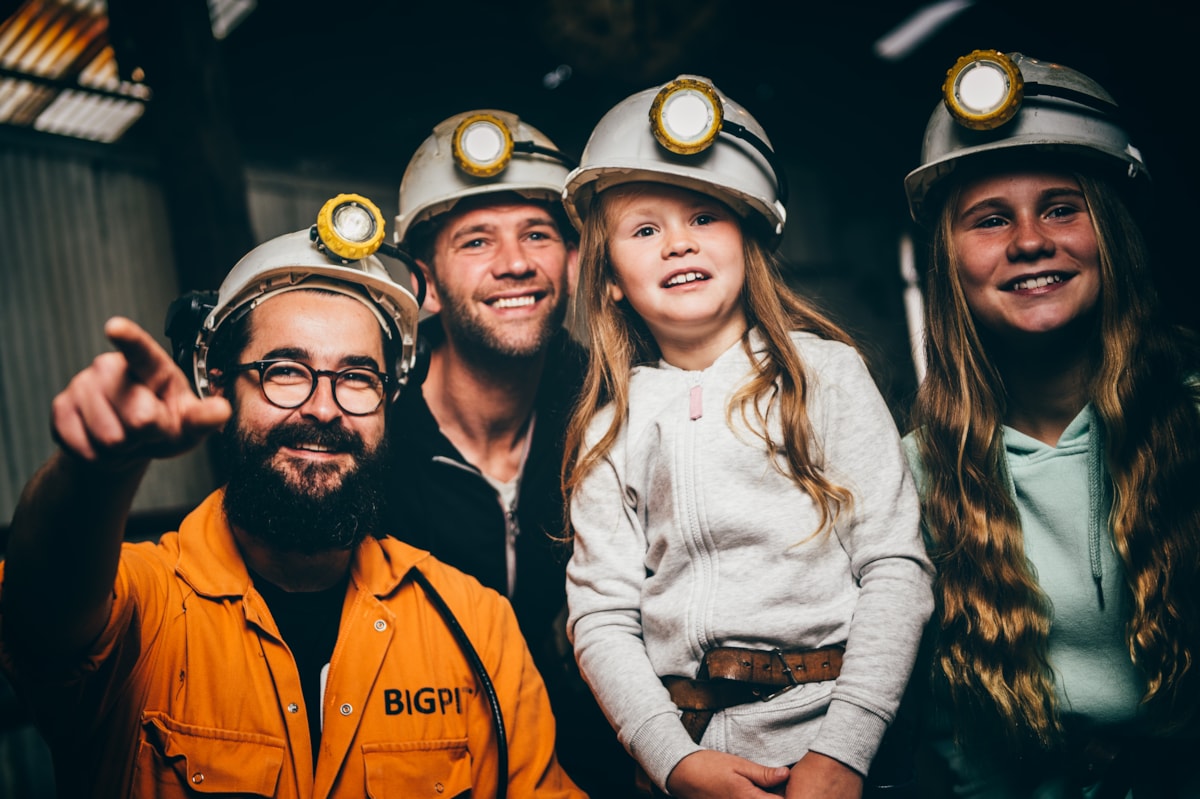 A smiling family getting ready for the Underground Tour at Big Pit with one of the Museum's guides