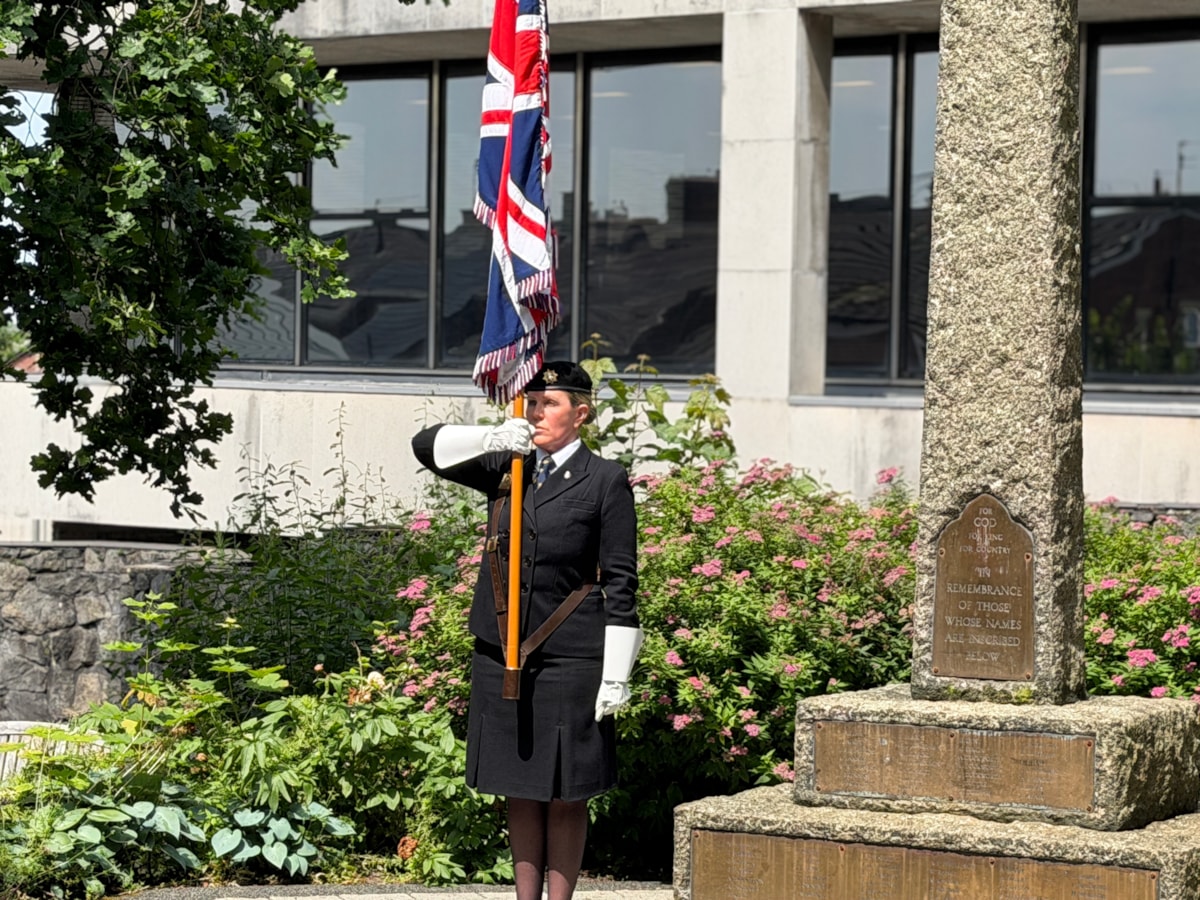 A standard bearer displays the Union Jack flag  next to the war memorial at County Hall before the flag raising ceremony to mark Armed Forces Day