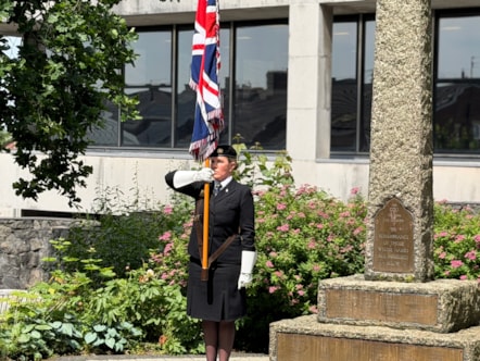 A standard bearer displays the Union Jack flag  next to the war memorial at County Hall before the flag raising ceremony to mark Armed Forces Day