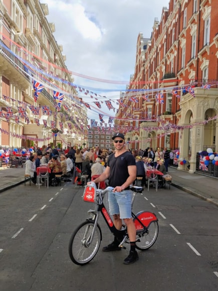 Christine’s photograph of her partner Jeff on a Santander Cycle on the Coronation Day of His Royal Highness King Charles III as they spontaneously stumbled upon a street p