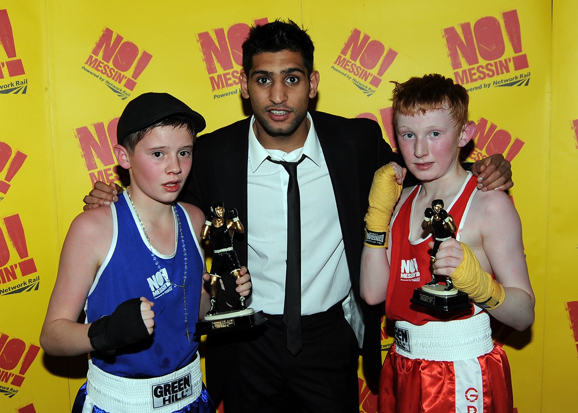 Portsmouth's Jack Featherstone (blue) and Lochaber's James Aitchison (red) collect their trophies from champion boxer Amir Khan at the No messin' tri-nation boxing competition: Portsmouth's Jack Featherstone and Lochaber's James Aitchison collect their trophies from champion boxer Amir Khan at the No messin' tri-nation boxing competition<br />