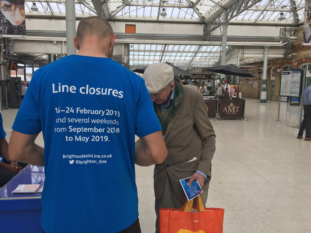 Passengers reminded to check ahead for weekend closures on the Brighton Main Line in October: Passenger picking up information at Eastbourne station about the line closures