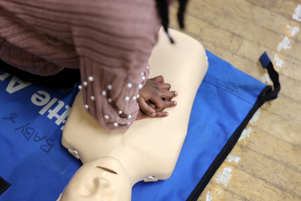 Child performing CPR on dummy