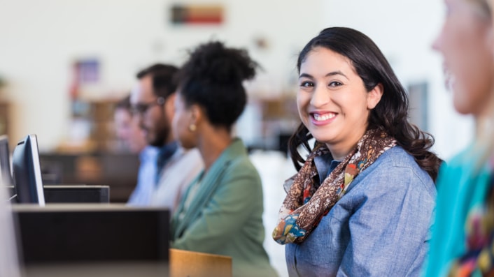 Woman sitting at a screen smiling (image)