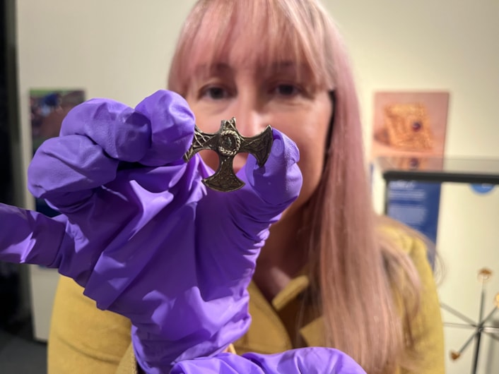 Saxon cross display: Curator of archaeology Kat Baxter with the ancient Saxon cross now on display at Leeds City Museum.
Believed to have once been a prestigious badge of office and a sign of religious identity, the silver, gilded pendant was discovered by a metal detectorist, with one of its four arms broken, and its central stone missing.
Newly created drawings, penned by archaeological illustrator John Prudhoe, show how the complete cross could have looked with its thin layer of gold leaf shining and a beautiful central garnet.