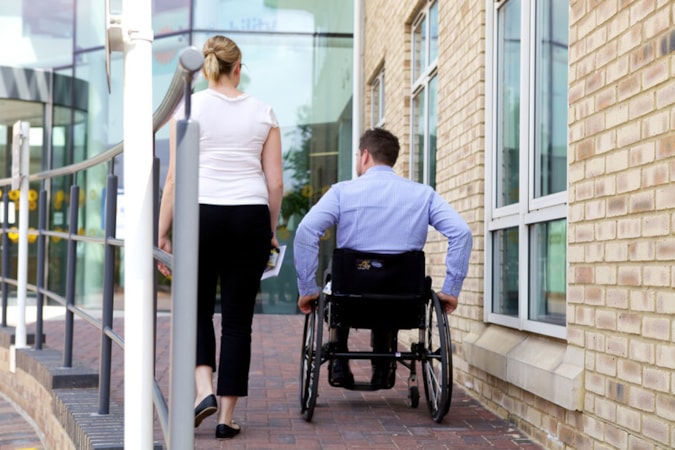 468 2013 Bristol employee photoshoot: Woman walks up ramp next to man in wheelchair, photographed from behind