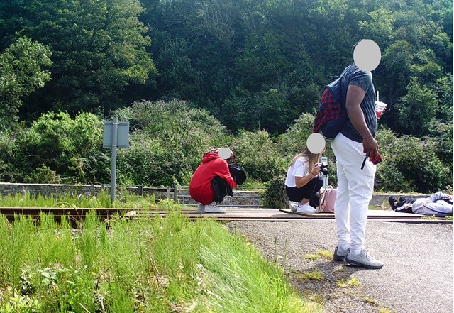 A younster lies on the tracks while others take pictures in Harlech