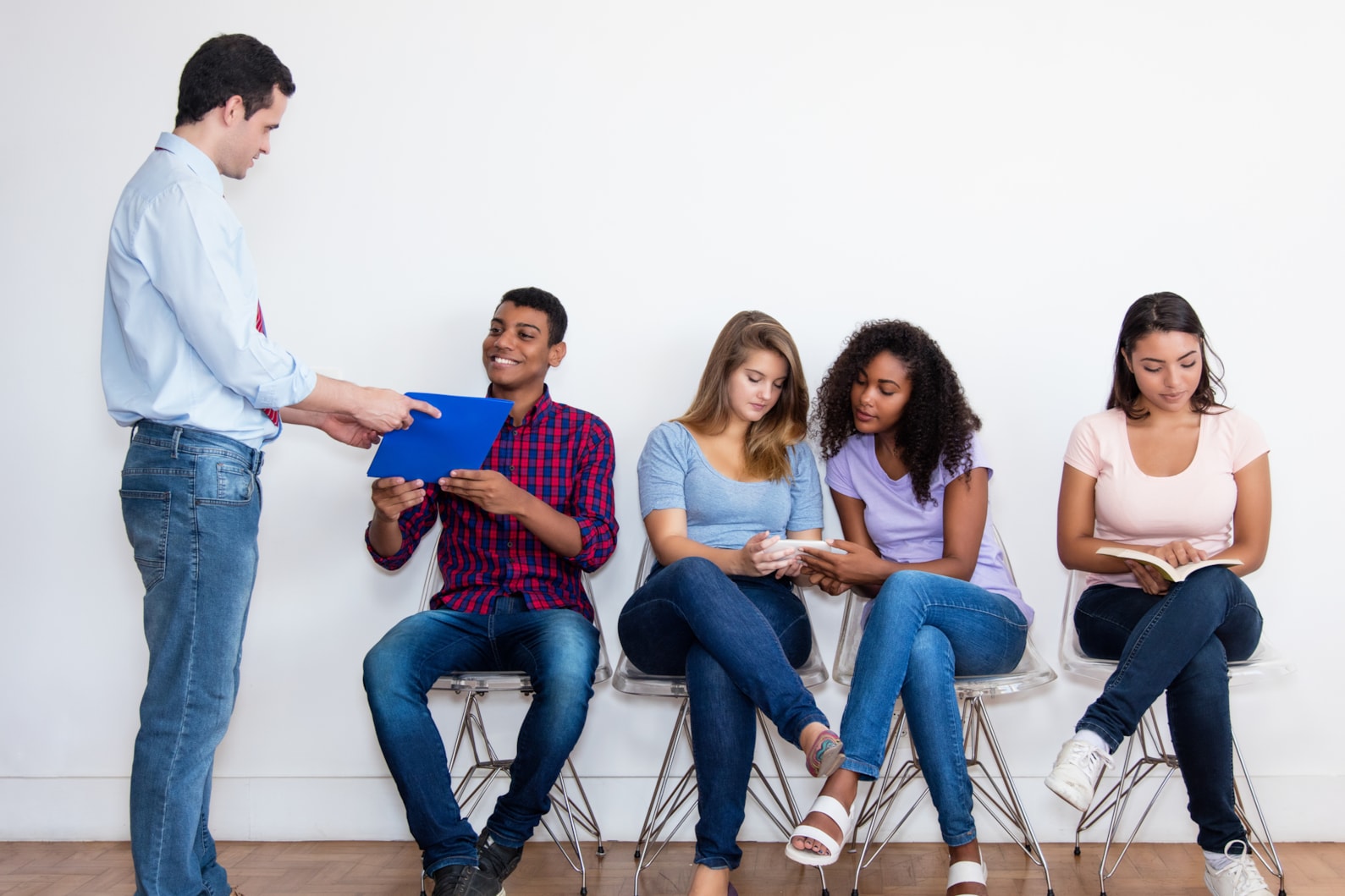 Understanding refugee employment for social service employers (image): Man talking with candidates waiting for job interview.
