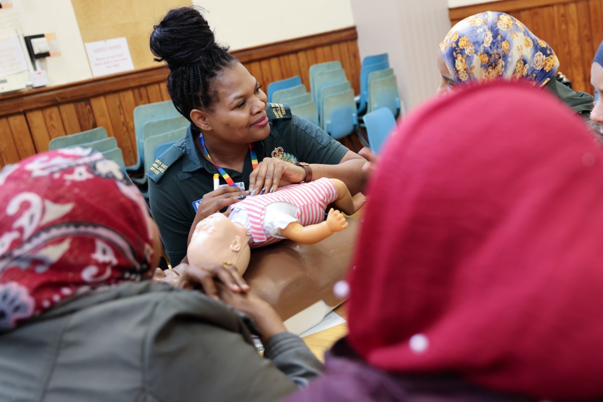 NEAS positive action officer showing child CPR to women