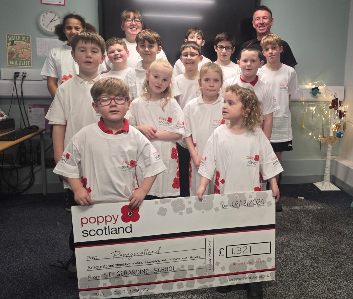 A group photo of the Poppy Scotland cheque handover event at St Gerardine Primary School. 

Front to back, left to right: Alex Webb, Connie Morris, Callum Innes, Layla Appleton, Penny Wagstaff, Fraser Beagrie, Eli Mitchell, Jack Dowds, Rohan Oakley, Cooper Struthers, Tiana Haydes, Miss Bromham, Euan