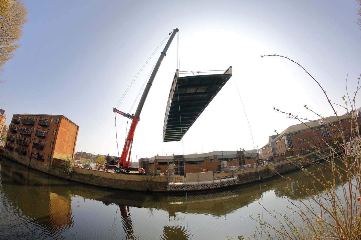 David Oluwale bridge installation: The David Oluwale bridge is lifted into place over the River Aire in Leeds. Engineers working on the David Oluwale bridge completed one of the project’s major milestones over the weekend, with cranes carefully placing the 40 tonne structure over the river where it will connect Sovereign Street to Water Lane. Credit BAM Nuttall.