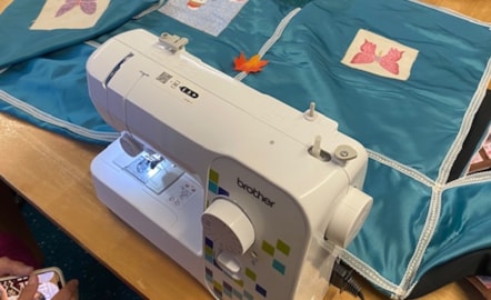 A sewing machine being used to help make a blue incubator cover