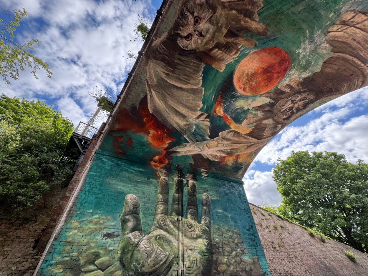 Mural Penny Pocket Park-4: Located on Church Walk in the viaduct under the railway tracks, the new mural incorporates two giant owls flying overhead, underwater scenes and a carved face emerging from a rock wall.