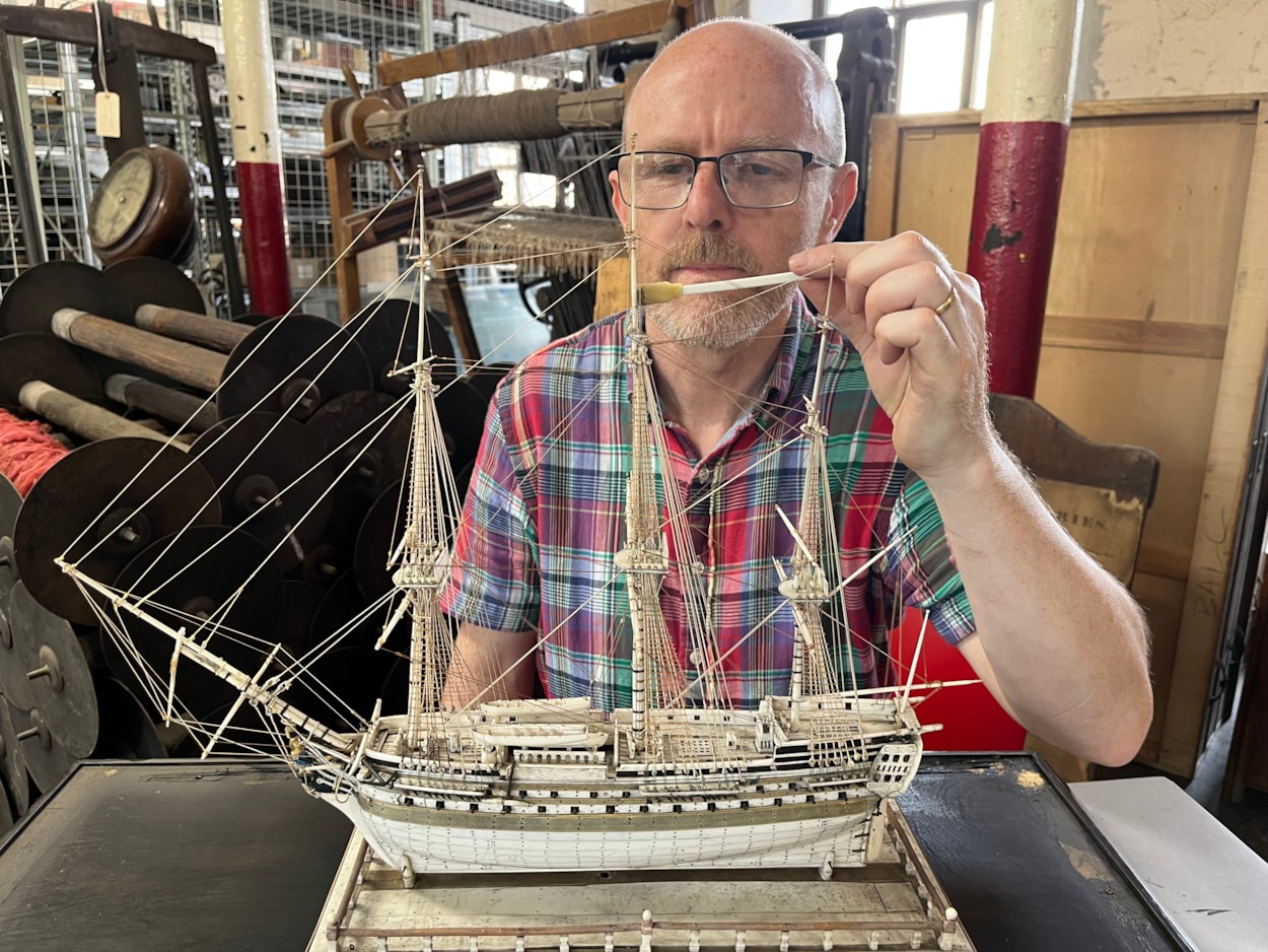 Model ships: Curator John McGoldrick with an intricate model ship carved from bone by a French prisoner during the Napoleonic Wars.
Complete with an elaborate figurehead, planked deck and carved helm with a steering gear and compass box, the bone model dates from the early 19th century and is believed to be an example of the type carved by French captives held in British prisons and aboard ships.