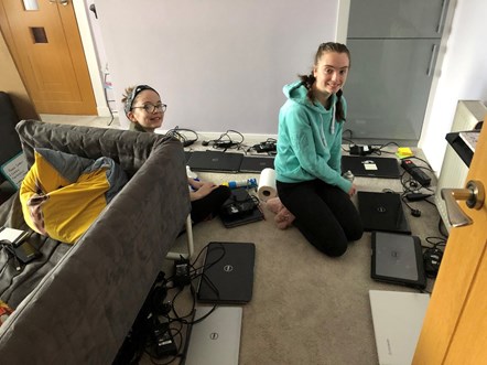 Smiling Lily and Katie Dunbar with laptops set out on floor
