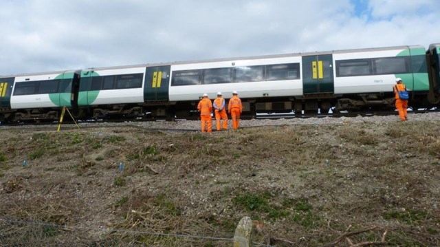 Ripe landslip: A Southern train gingerly makes its way across the landslip at 5mph while staff stand back for safety reasons