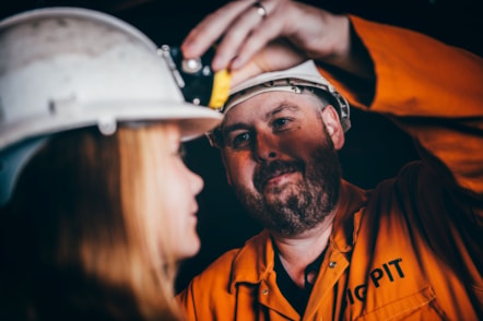 Tywyswr Big Pit yn helpu merch ifanc efo'i lamp ben