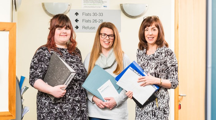 Three female housing support workers holding folders.
