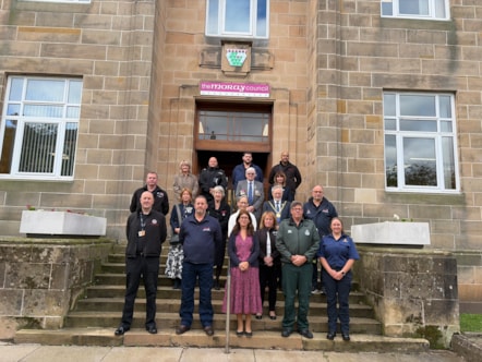 Moray Council Leader, Cllr Kathleen Robertson (centre) with Civic Leader, Cllr John Cowe, second row, are joined by Moray Council Chief Executive, Karen Greaves; Executive Director Economy, Enterprise and Operations, Rhona Gunn; Cllr Peter Bloomfield and members of Moray's emergency services from Po