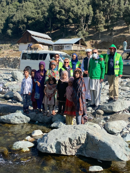 Helen Bingley and charity trustees, with children in Swat Valley, Pakistan, standing where their homes used to be