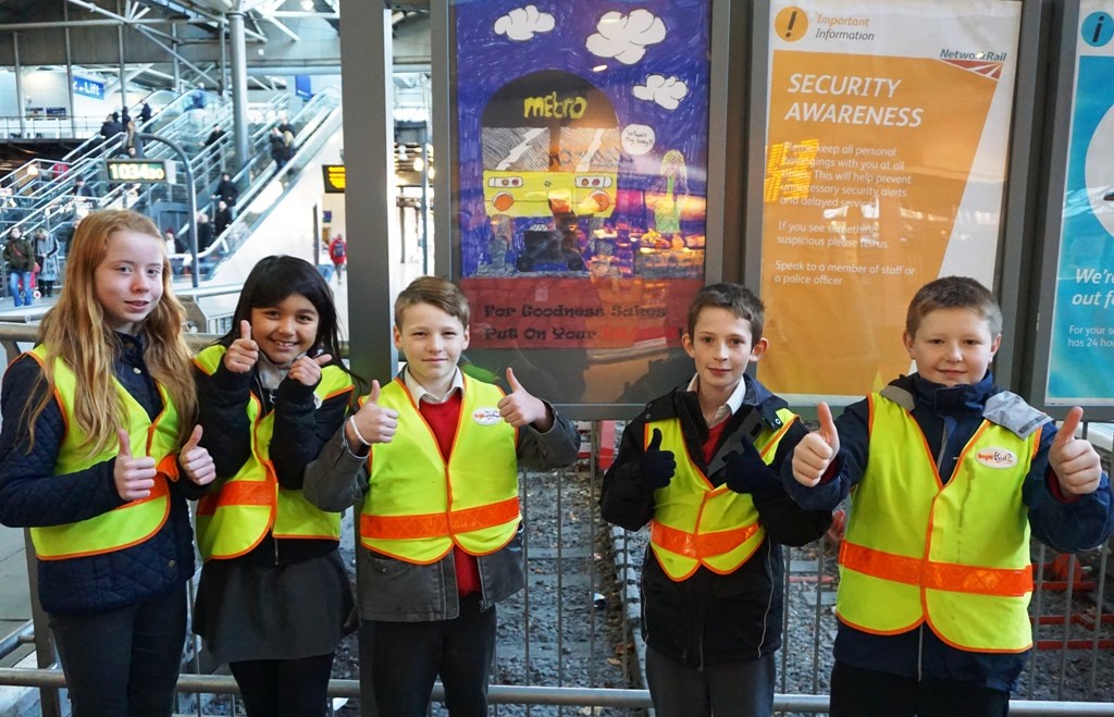Pupils' safety posters for Leeds station: The children pose with Dylan's design at Leeds station