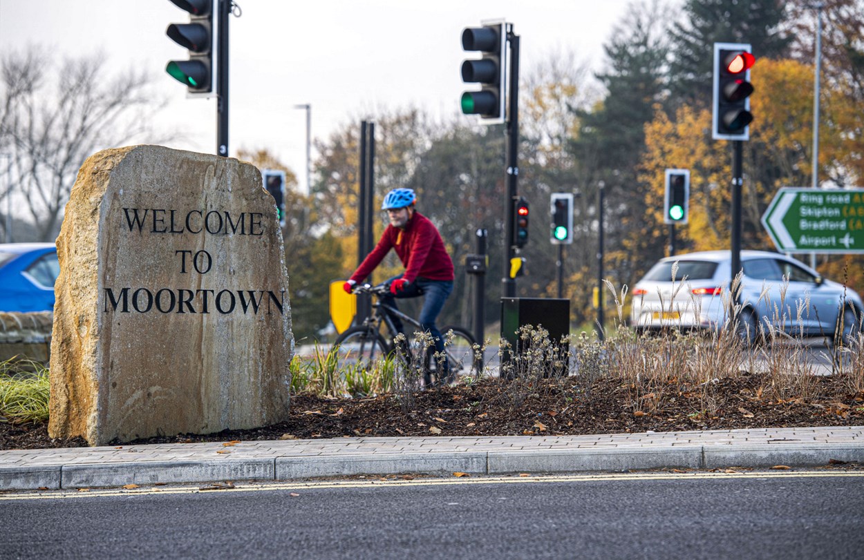 Person cycling past Welcome to Moortown sign