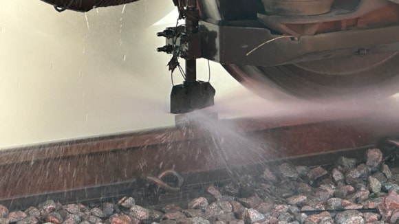 High pressure water jet spraying rail - A water jet on a leaf-busting train, which removes leaf residue as the train travels.