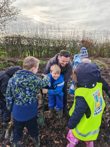 Councillor Joshua Roberts helps youngsters stuck in the mud while planting trees