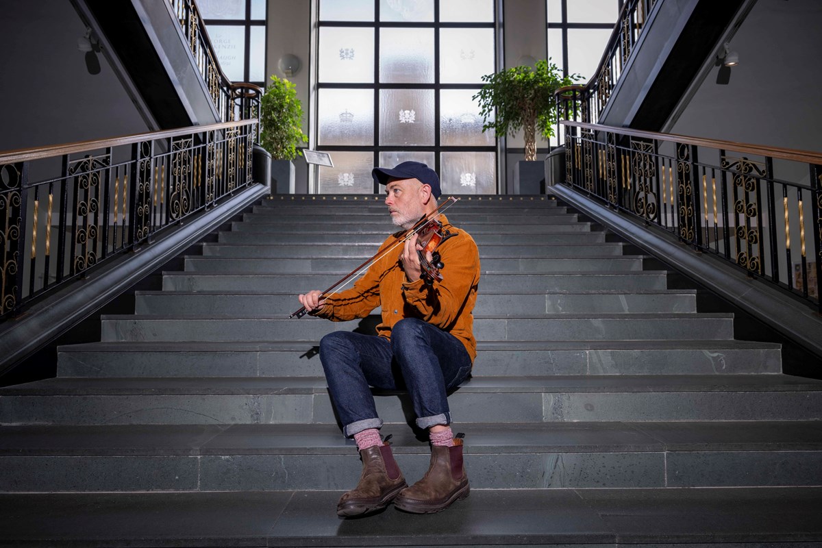 Fiddler Aidan O'Rourke on the main stairs of the foyer in the National Library of Scotland's George IV Bridge building. Credit: Neil Hanna