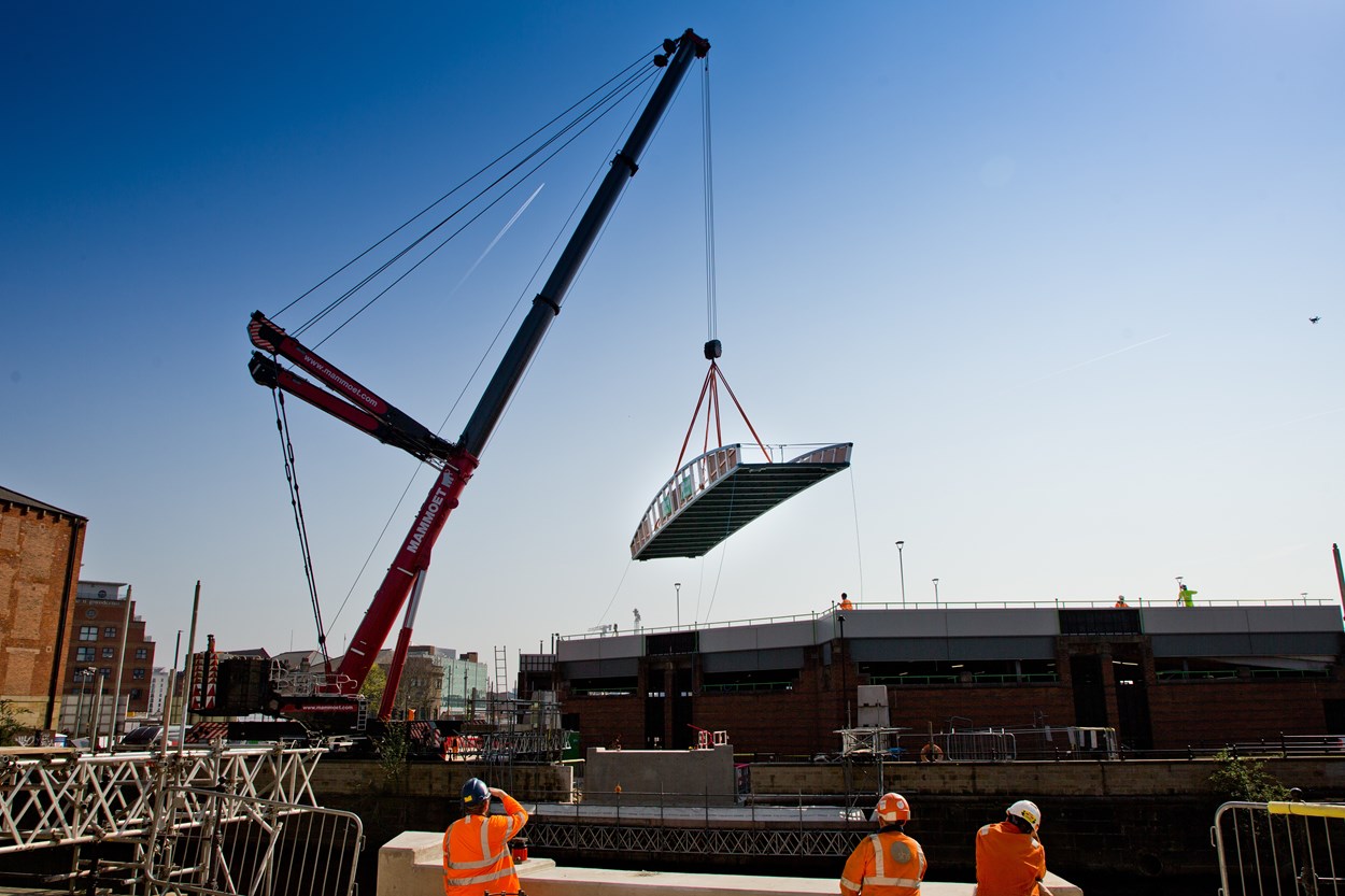 David Oluwale bridge installation: The David Oluwale bridge is lifted into place over the River Aire in Leeds. Engineers working on the David Oluwale bridge completed one of the project’s major milestones over the weekend, with cranes carefully placing the 40 tonne structure over the river where it will connect Sovereign Street to Water Lane. Credit BAM Nuttall.