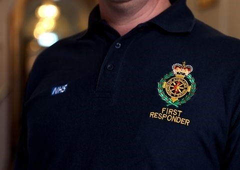 A close up of a dark-coloured NEAS first responder uniform top showing the NEAS badge and text 'First Responder'.