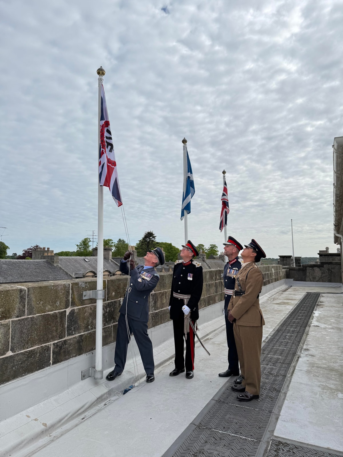 Military personnel with LL Banffshire and LL Moray raising VE Day 80 flag
