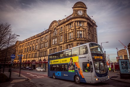 A Go North West bus passing Manchester's Victoria Building
