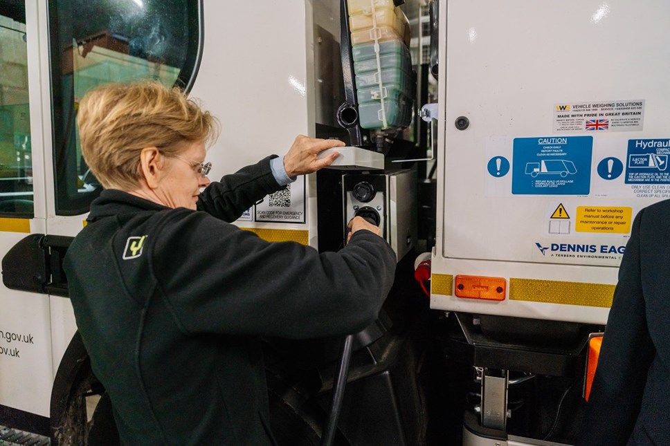 Cllr Champion plugs an electric charging cable into a refuse collection