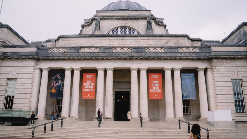 Golygfa o du allan i Amgueddfa Genedlaethol Caerdydd wrth i ymwelwyr fynd at y fynedfa.