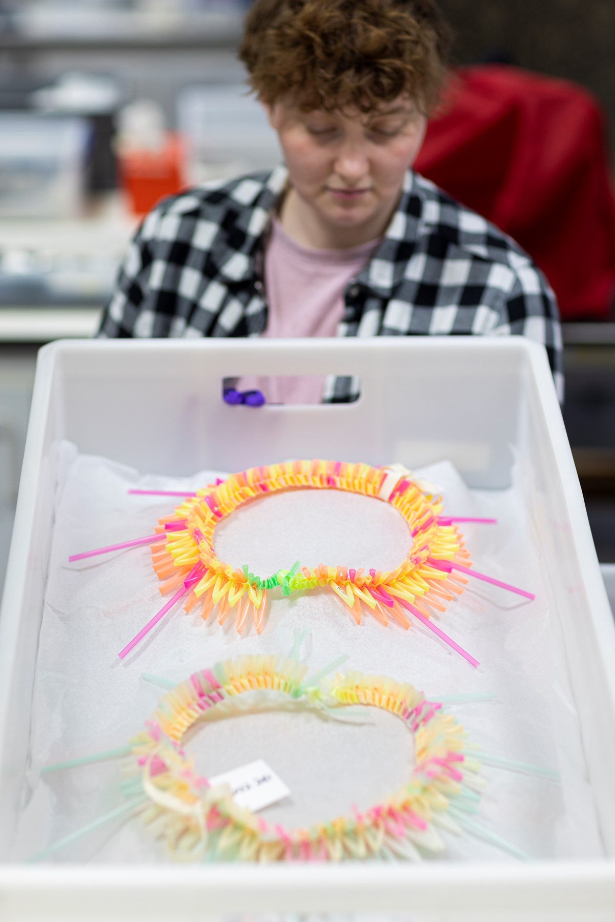 Laura Marsh, conservation intern with Te Tai (dance headdresses) by Kaetaeta Watson and Louisa Humphry, recycled plastic straws (2022) © Duncan McGlynn