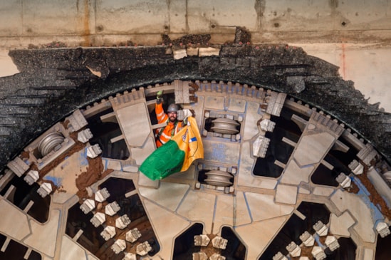 HS2 tunnelling miner gives thumbs up holding flag of Donnegal after completing the breakthrough of TBM Mary Ann in Birmingham: The flags represent the nationality and regions of the expert tunnelling teams who have completing the tunnelling mission