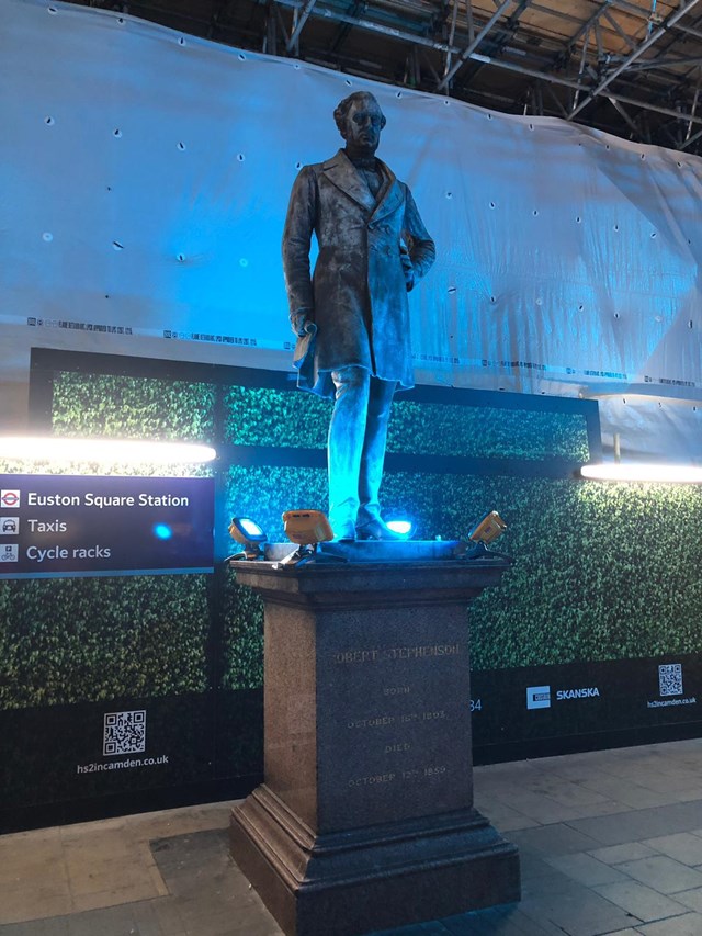 Robert Stephenson statue bathed in blue light at Euston