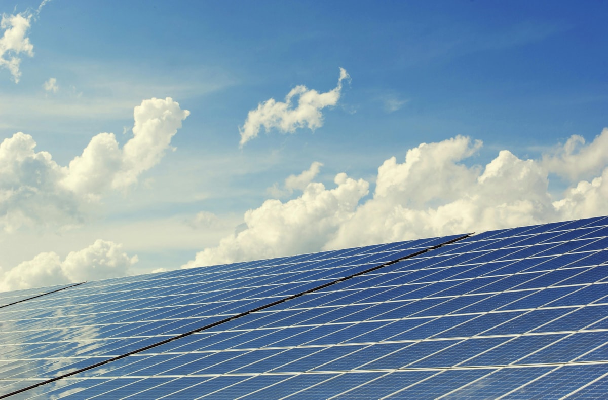 Solar panels against a blue sky with white clouds.