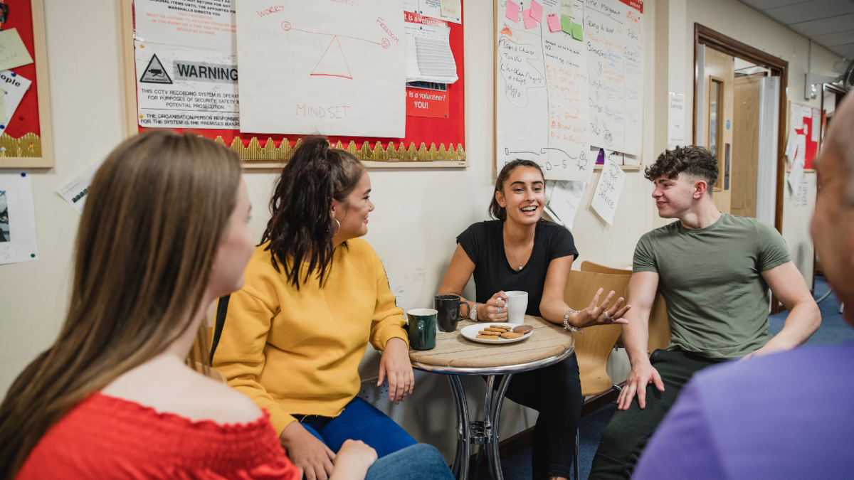 A group of young people sitting around a small table, smiling and talking