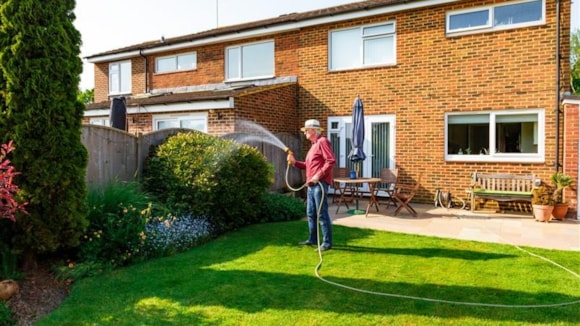 Pioneering new study tests how a simple ice slushy could protect against heat exhaustion for the elderly and vulnerable: Picture of a man watering his back garden on a sunny day