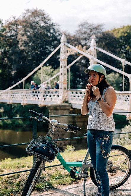 Lady putting on her helmet by a bridge stood by a Beryl bike
