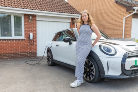 E.ON Next customer Abi is pictured standing next to her EV which is plugged into a charger on her drive.