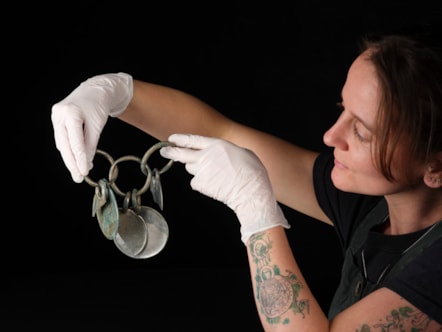 Conservator Bethan Bryan holds the bronze rattle pendant. Photo © National Museums Scotland (1)