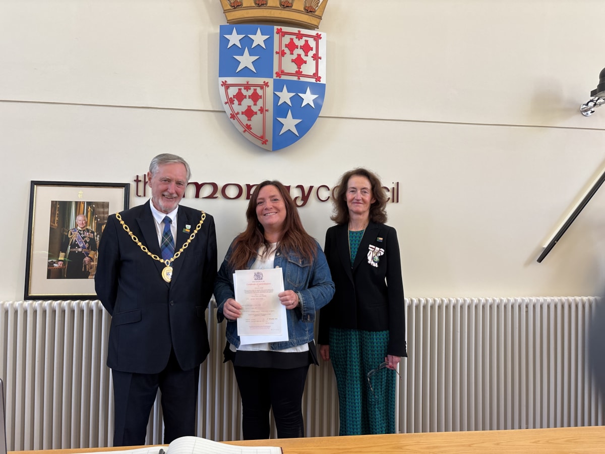 Stacie Whitney (Centre) receiving her citizenship certificate from Moray Council Civic Leader Cllr John Cowe and Vice Lord-Lieutenant of Moray, Nancy Robson.