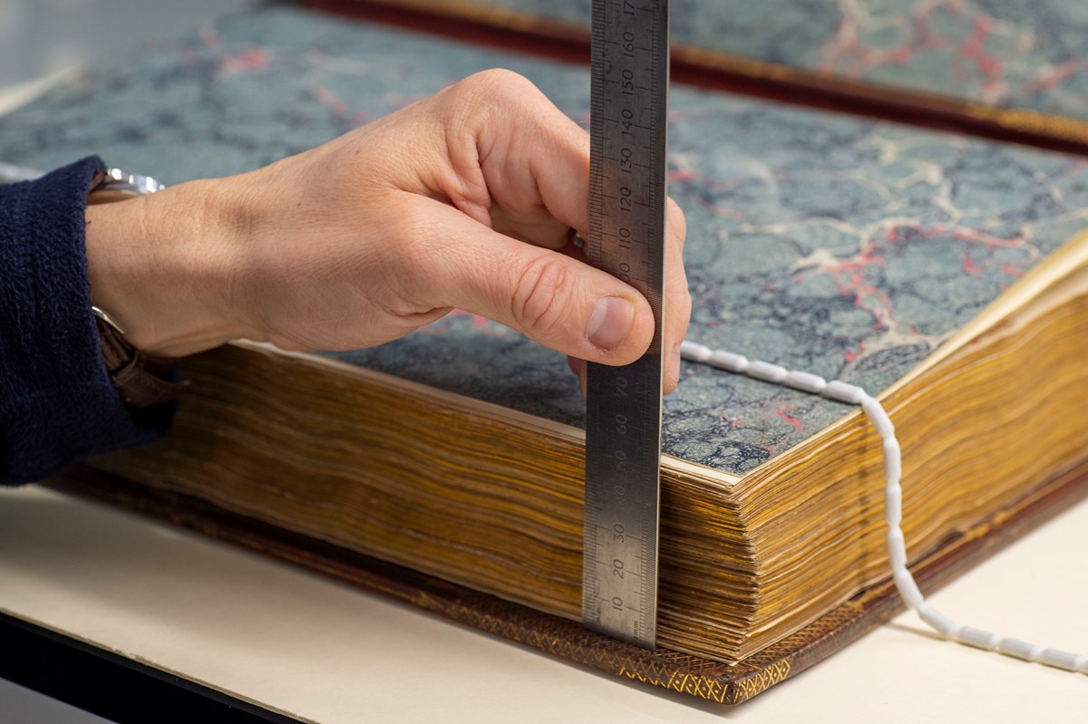 A Library conservator inspects the Library's copy of the Gutenberg Bible before it is installed at the Treasures of the National Library exhibition. Credit: Neil Hanna