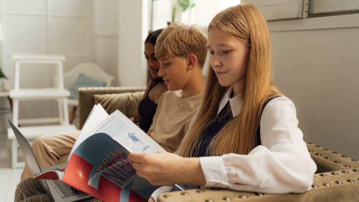 Teenagers reading on sofa cropped